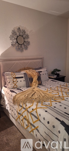 A bed with a white and grey comforter and a decorative pillow is in the image.