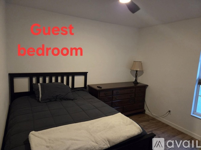 A guest bedroom with a bed, nightstand, and lamp.