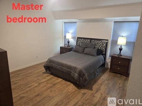 A master bedroom with a large bed and two lamps.