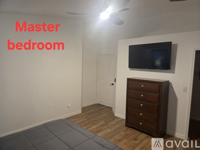 A bedroom with a television and a dresser.