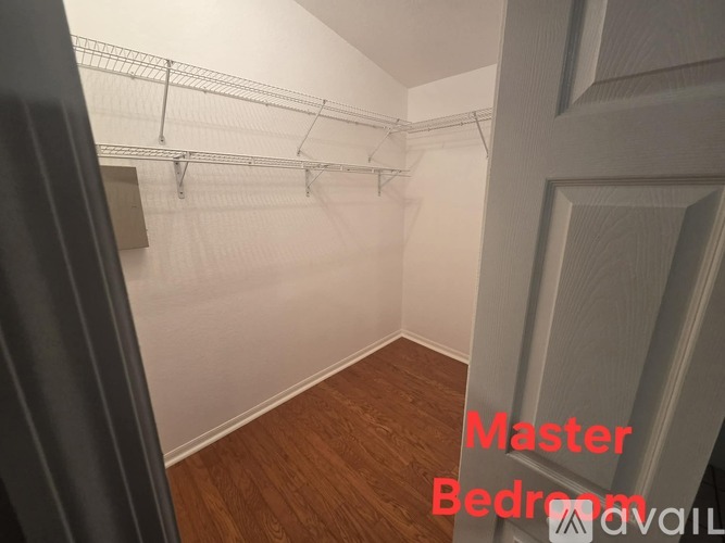 A room with a wooden floor and white walls, with clothes hanging on a rack.