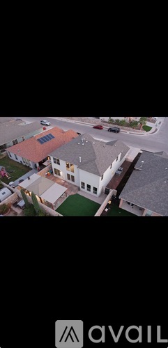A modern house with a red roof and a green lawn.