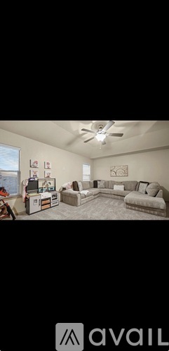 A living room with a couch, a television, and a ceiling fan.