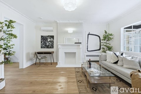 A living room with a white couch, a fireplace, and a painting on the wall.