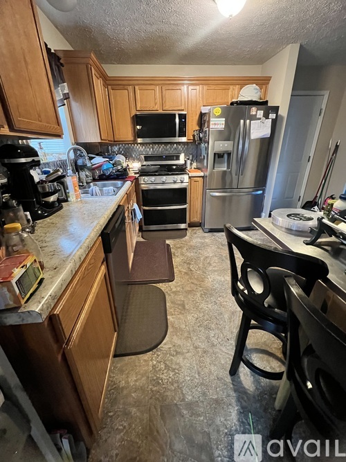 A kitchen with wooden cabinets and a stainless steel refrigerator.
