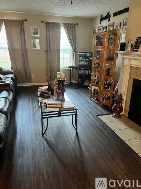 A living room with a black leather couch and a coffee table with books on it.