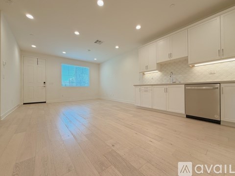 A spacious kitchen with white cabinets and a wooden floor.