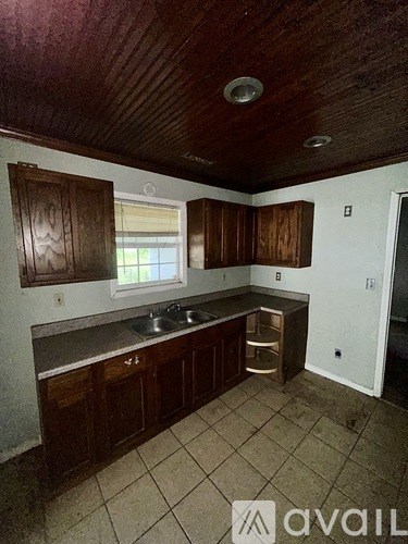 A kitchen with wooden cabinets and a tiled floor.