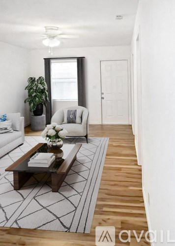 A living room with a white couch, a coffee table, and a potted plant.
