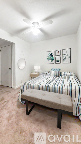 A bedroom with a bed, a ceiling fan, and a wall hanging.