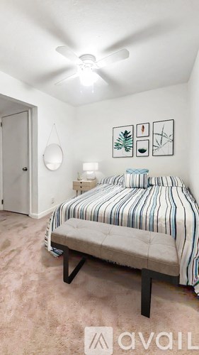 A bedroom with a bed, a ceiling fan, and a wall hanging.