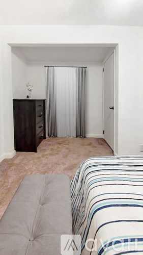 A bedroom with a bed, a cabinet, and a striped blanket.
