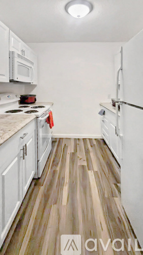 A kitchen with white cabinets and a wooden floor.