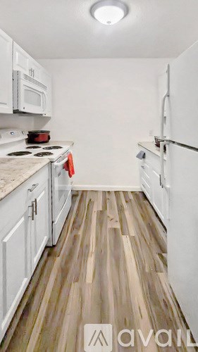 A kitchen with white cabinets and a wooden floor.