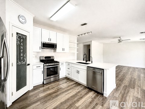 A kitchen with white cabinets and a black fridge.