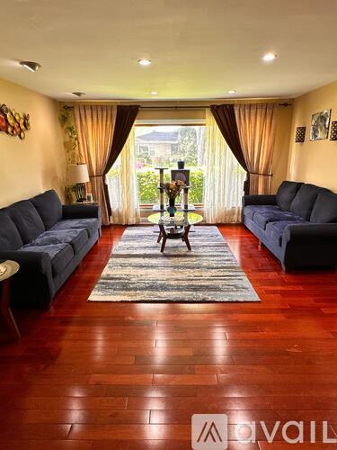 A living room with a wooden floor and two grey sofas.
