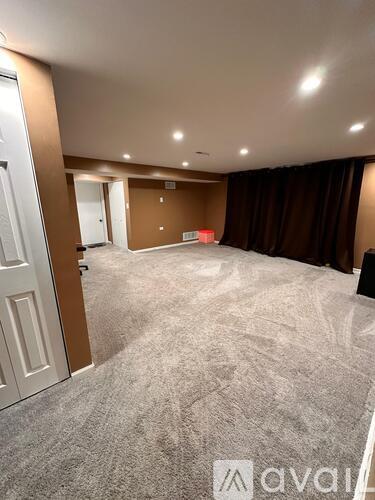 A spacious room with carpeted floor and brown walls.