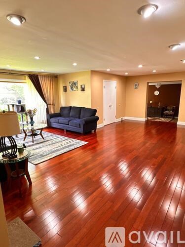 A living room with a blue sofa and wooden floors.