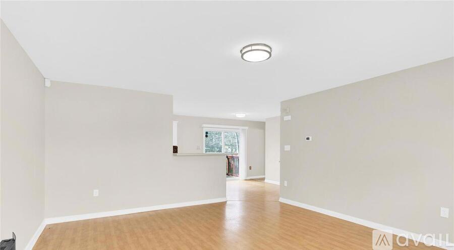 A spacious room with wooden floors and a large window.