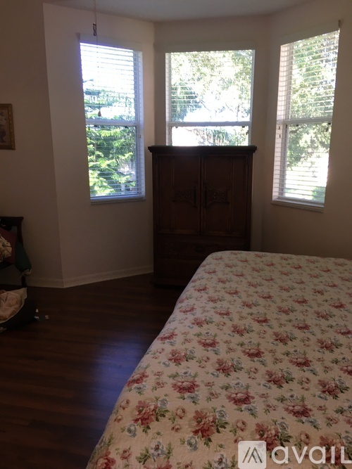 A bedroom with a floral bedspread and a wooden cabinet.