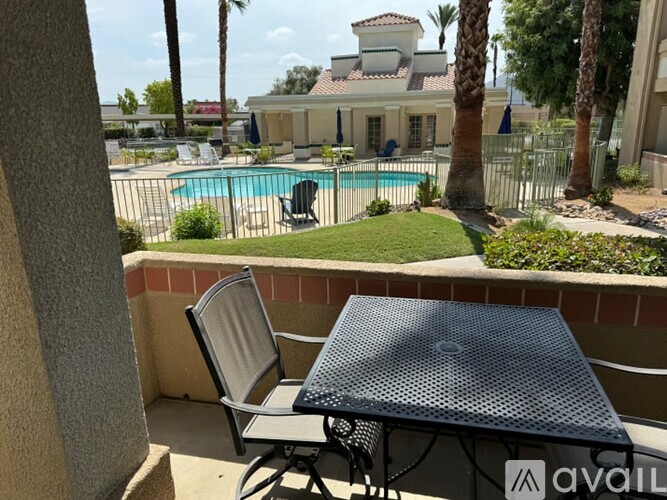 A patio with a table and chairs overlooking a pool.