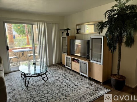 A living room with a glass coffee table and a television on a stand.
