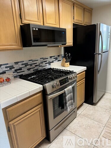 A kitchen with wooden cabinets and a black refrigerator.