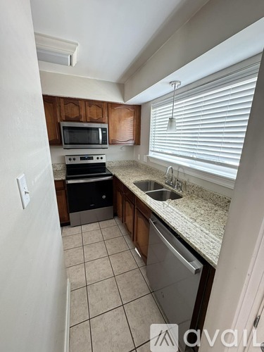 A kitchen with a sink, stove, and microwave.