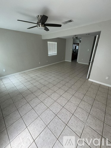 A spacious room with a ceiling fan and tiled flooring.