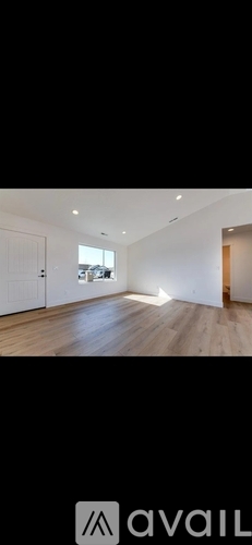 A spacious room with wooden flooring and white walls.