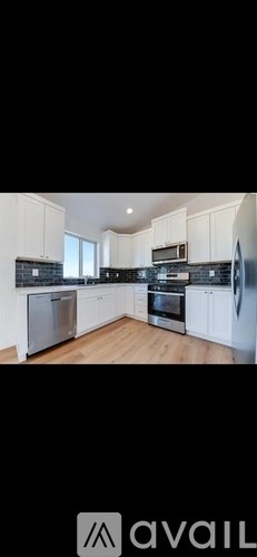 A modern kitchen with white cabinets and stainless steel appliances.