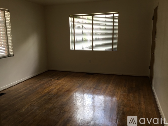 A room with wooden flooring and a window with blinds.