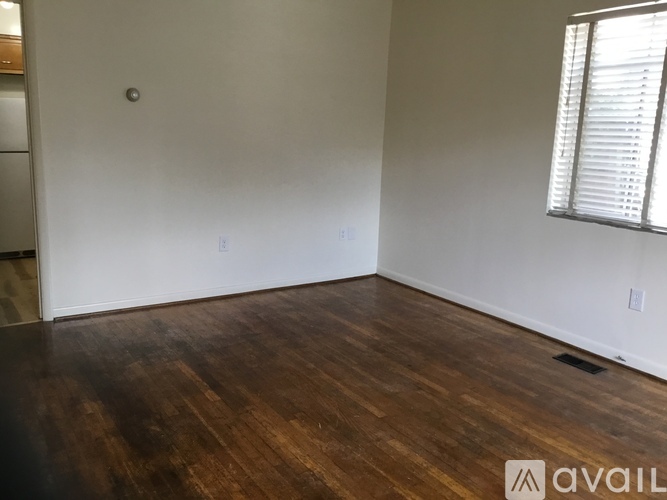 A room with wooden floors and a window with blinds.