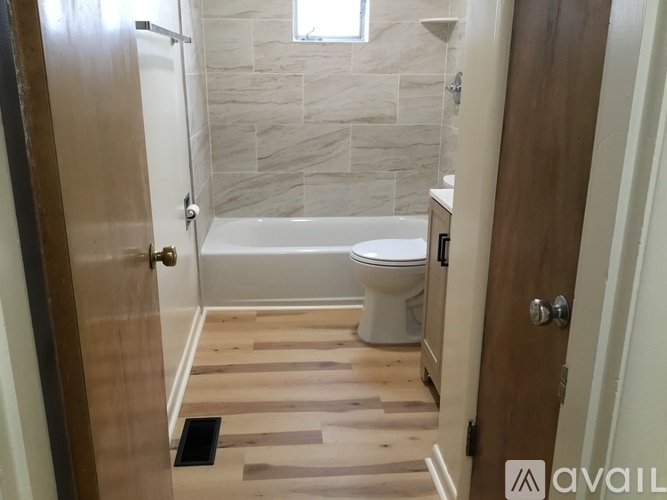 A bathroom with a toilet, tub, and wooden floors.