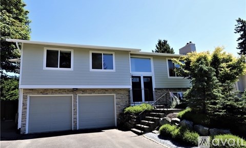 A two-story house with a garage and a stone wall.