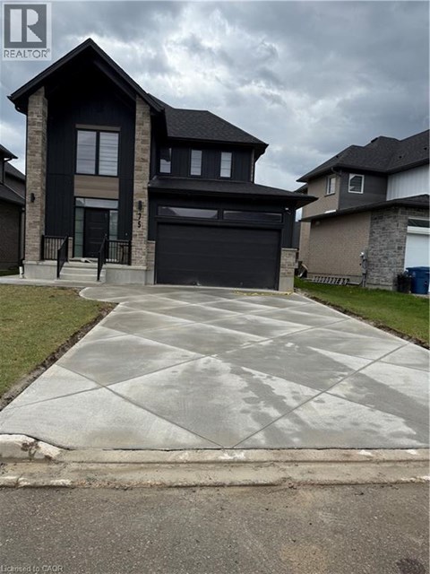A black house with a grey driveway in front.