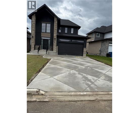 A house with a black garage door is in front of a cloudy sky.