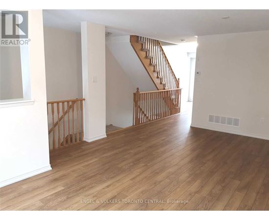A living room with a staircase and wooden floors.