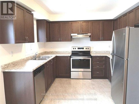A kitchen with brown cabinets and a stainless steel refrigerator.