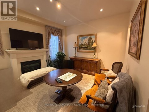 A living room with a fireplace, a television, a couch, and a painting on the wall.