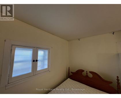 A bedroom with a bed, window, and a wooden headboard.