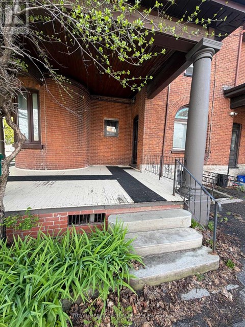 A red brick building with a black railing and a tree in front.