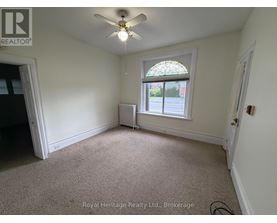 A room with a ceiling fan and a window with a view of the street outside.