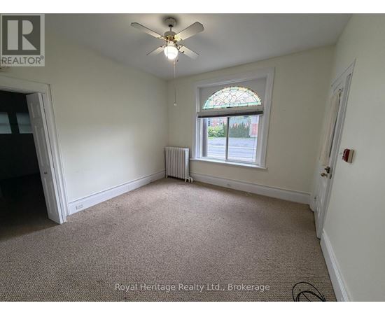 A room with a ceiling fan and a window with a view of the street outside.