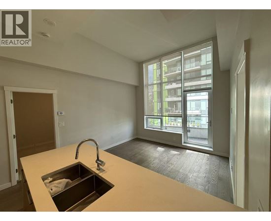 A kitchen with a sink and a window overlooking a building.
