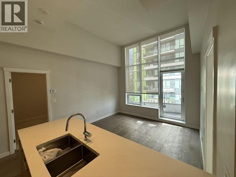 A kitchen with a sink and a window overlooking a building.