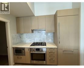A kitchen with a marble countertop and stainless steel appliances.