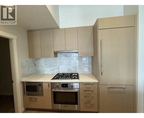 A kitchen with a marble countertop and stainless steel appliances.