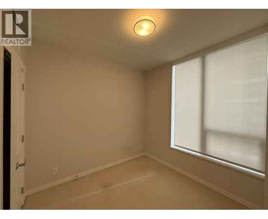 A room with a window and a carpeted floor.