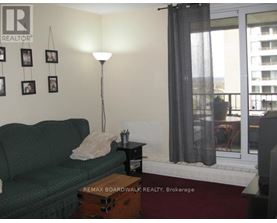 A living room with a green couch, a lamp, and pictures on the wall.